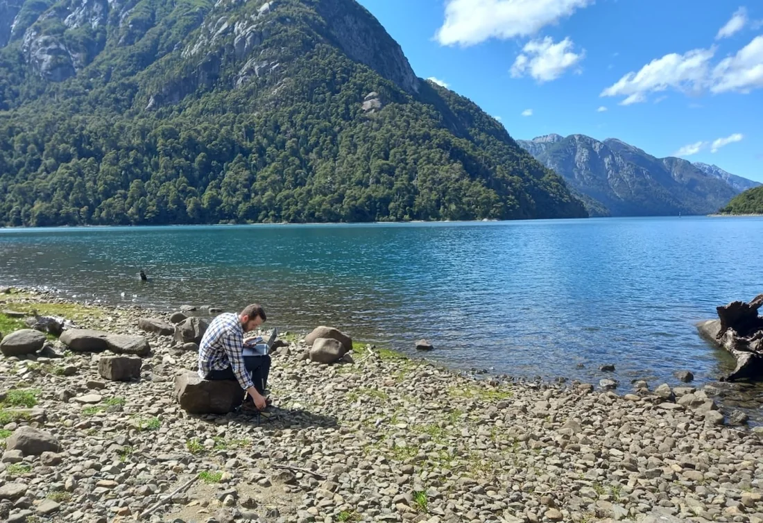 Patrick working with field equipment beside a lake in Patagonia
